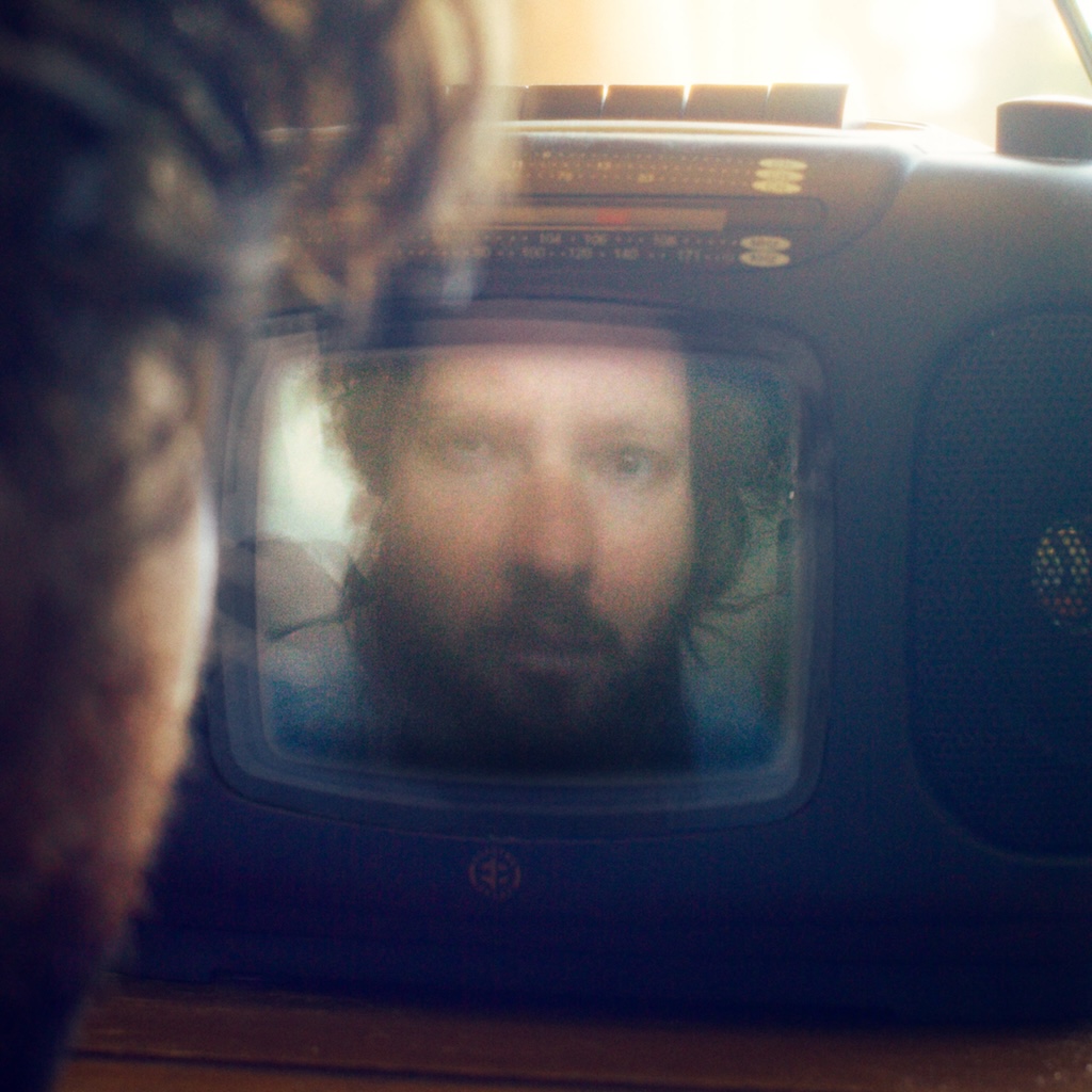 Cover art for Shut Up And Watch The Movie by Monte Lately. Looking over Monte Lately's shoulder as they look into a tv screen, seeing their face reflected in the screen.